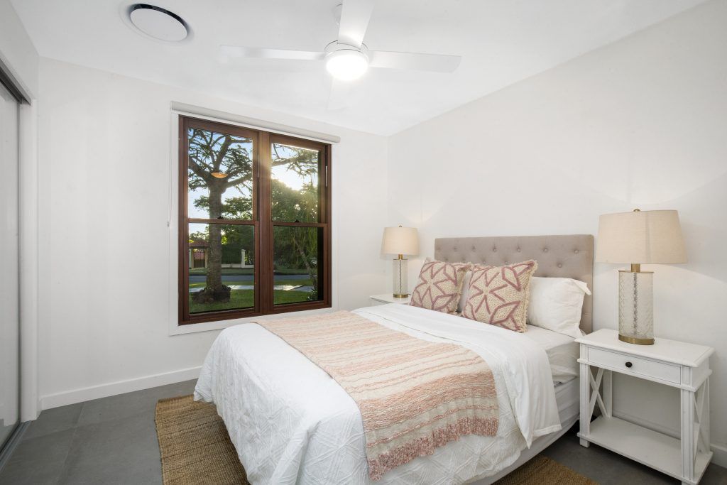 A bedroom with a bed , nightstand , lamps and a ceiling fan.