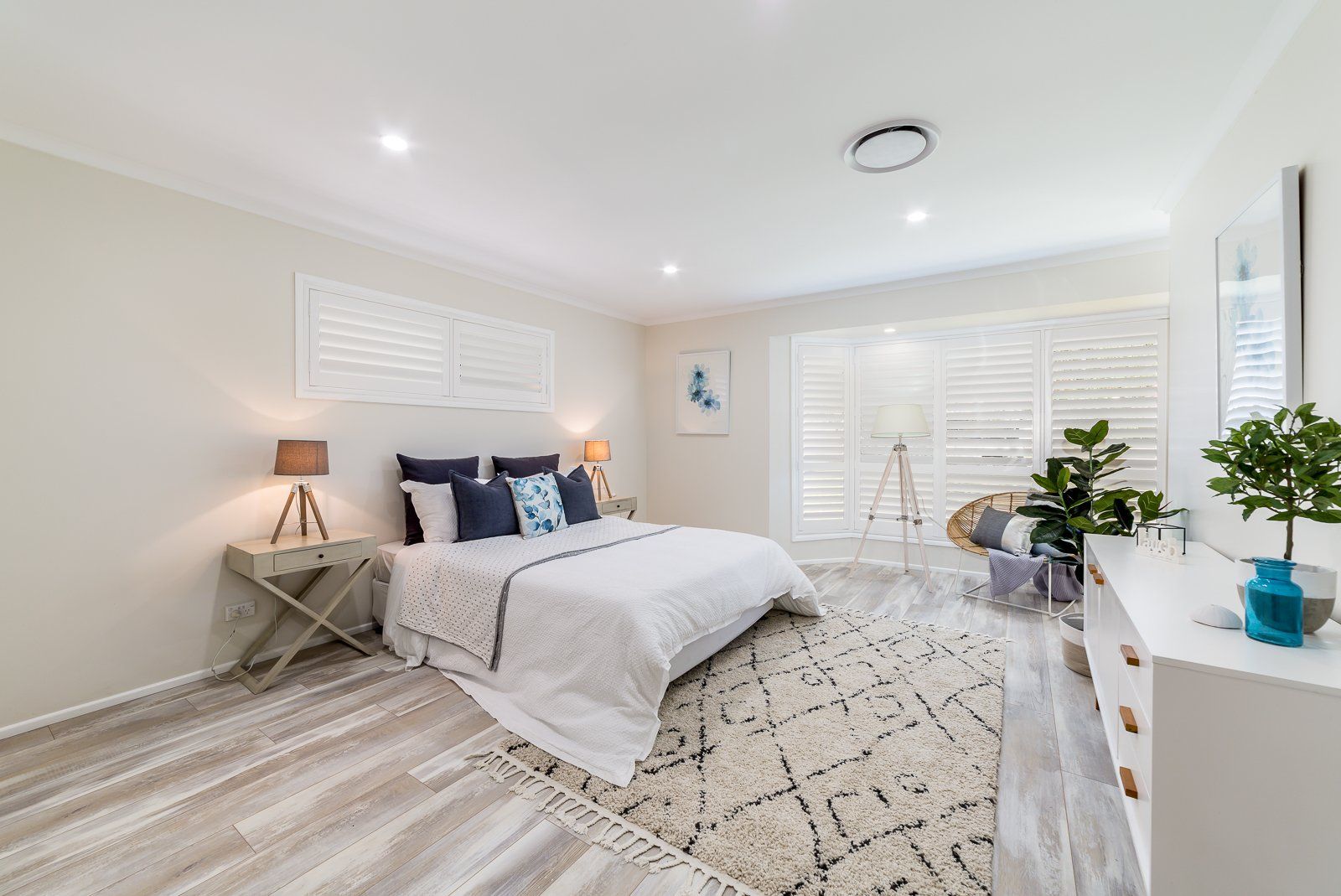 A bedroom with a bed , dresser , nightstand and rug.