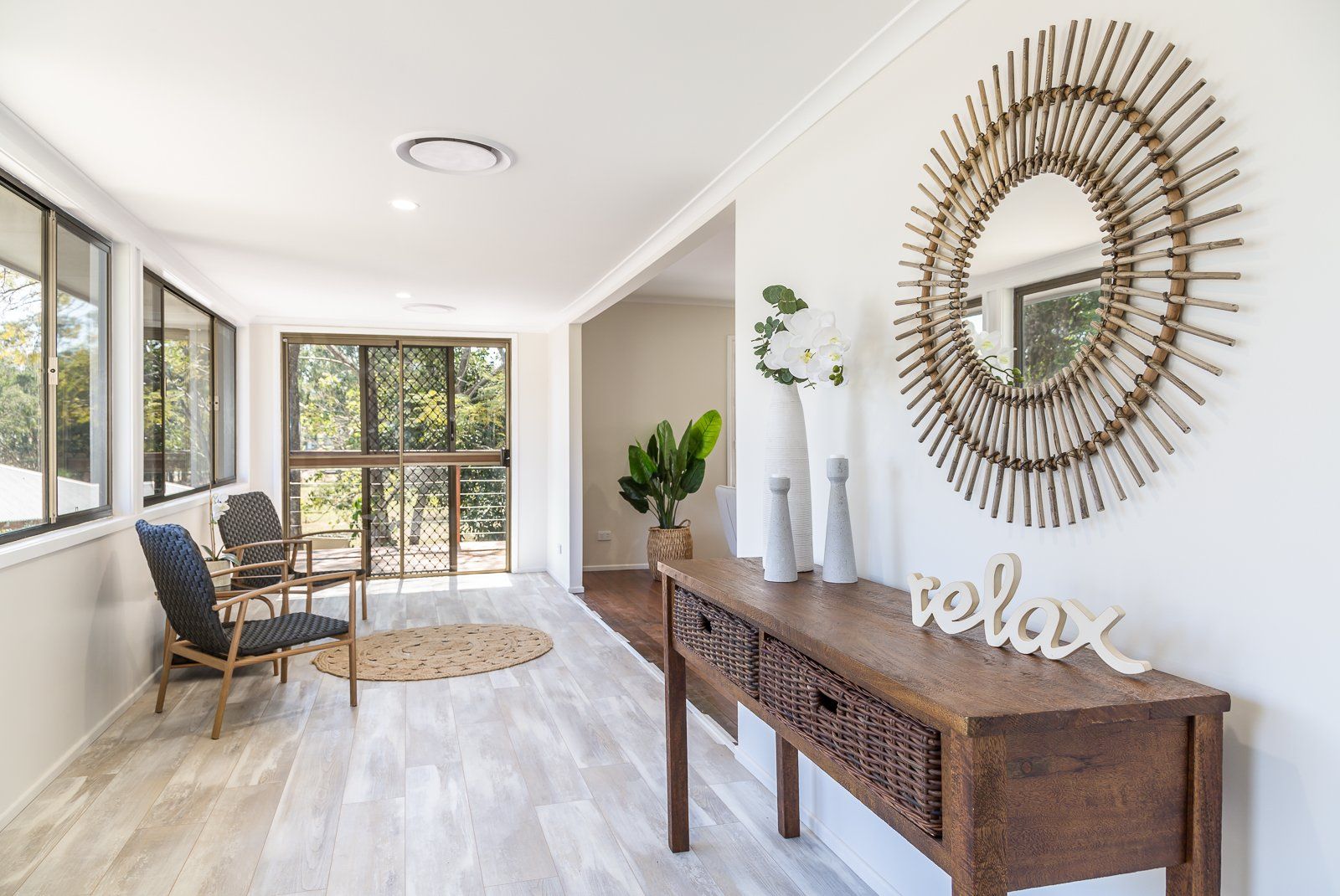 A living room with a wooden table , chairs , a mirror and a sign that says `` relax ''.