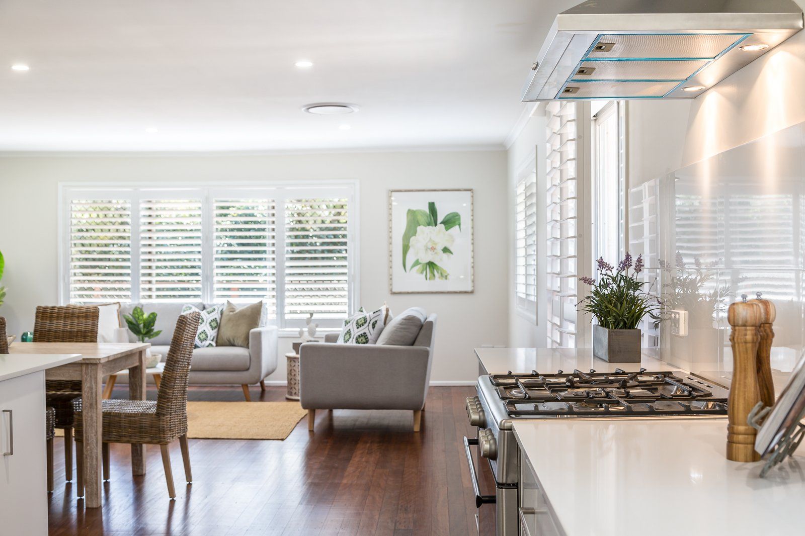 A kitchen with a stove top oven and a living room with a couch and chairs.