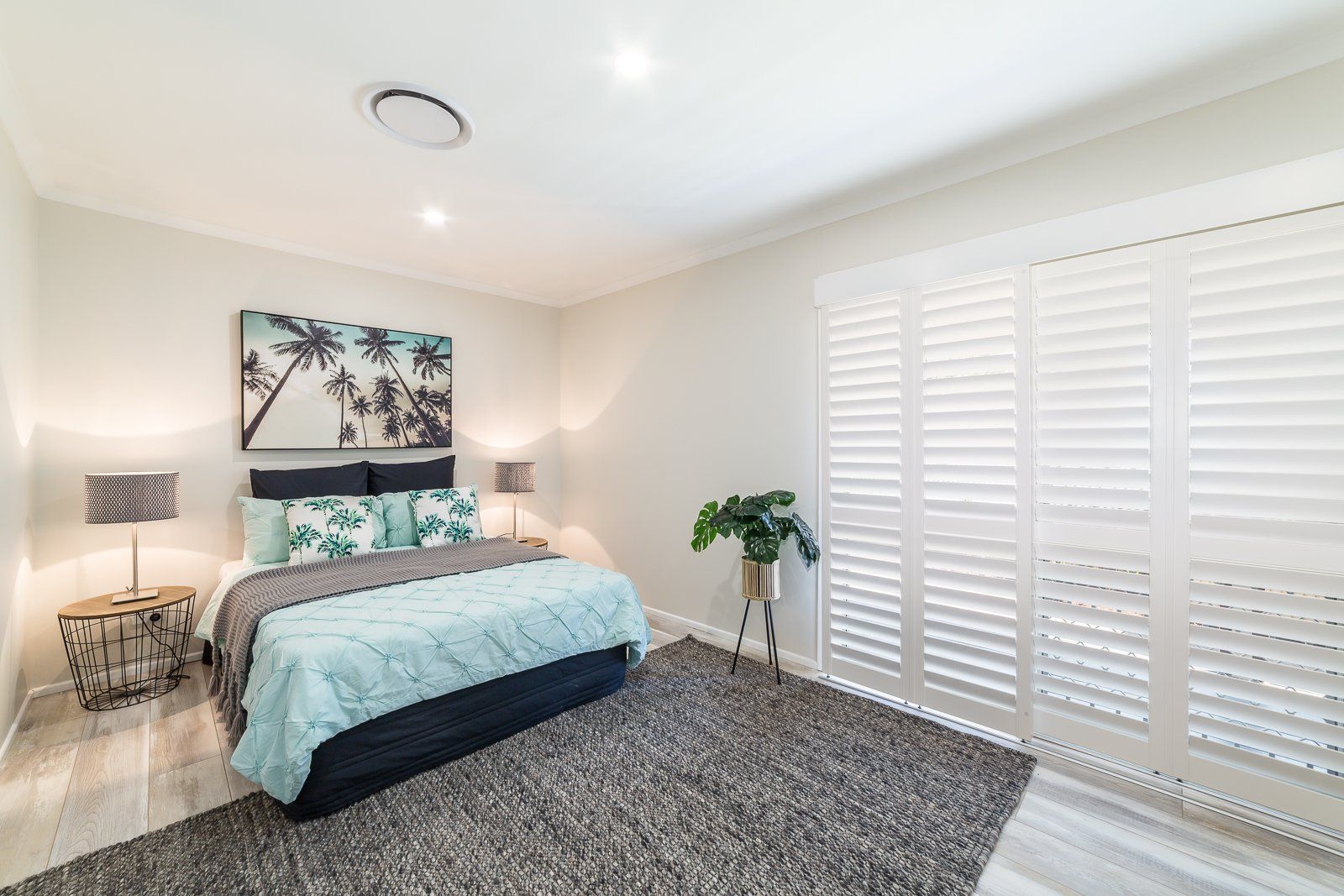A bedroom with a large bed and shutters on the windows.