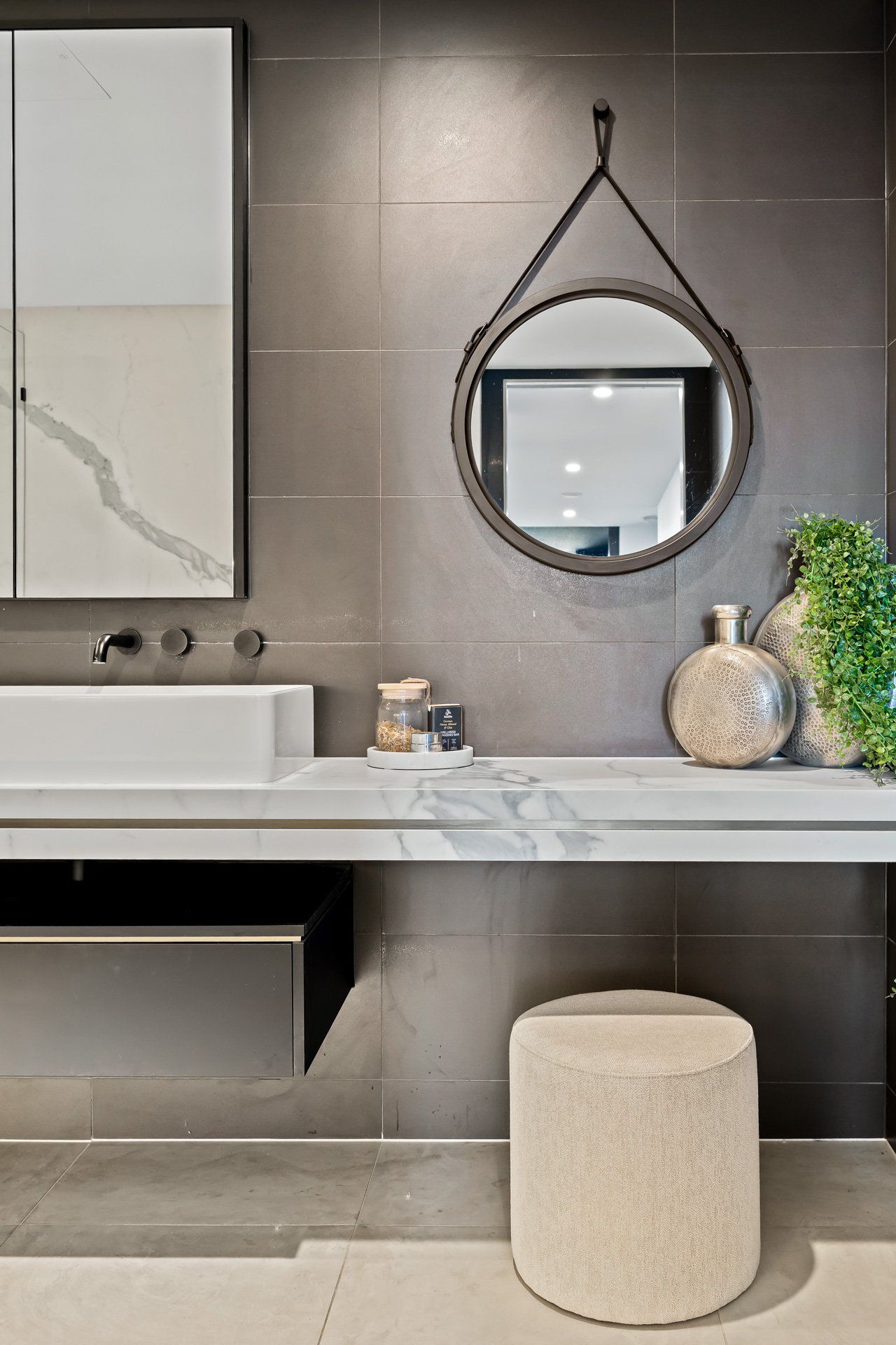 A bathroom with a sink , mirror and stool.