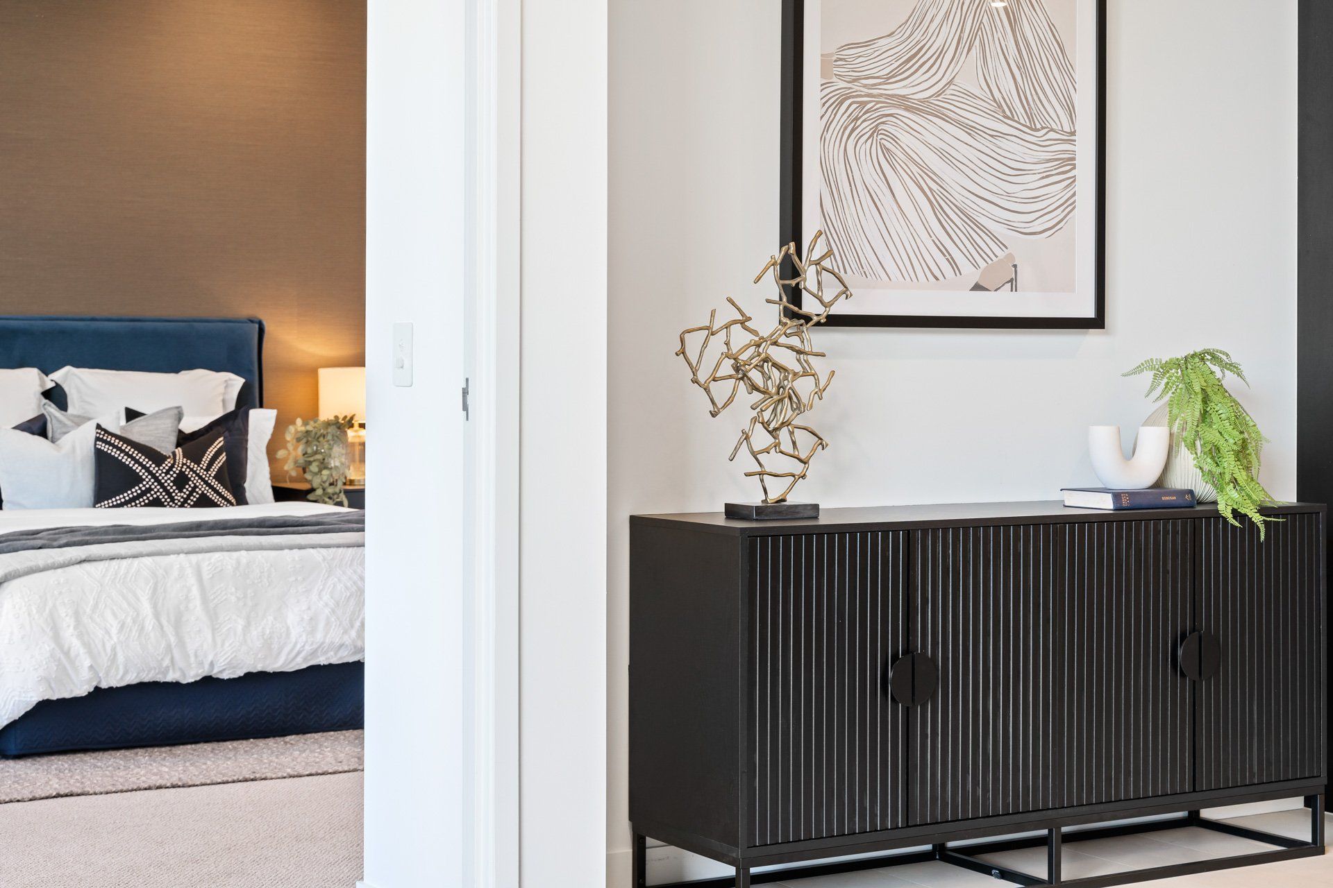 A bedroom with a black dresser and a bed.