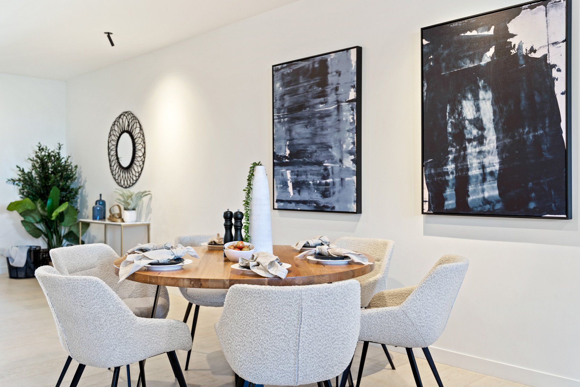 A dining room with a table and chairs and two paintings on the wall