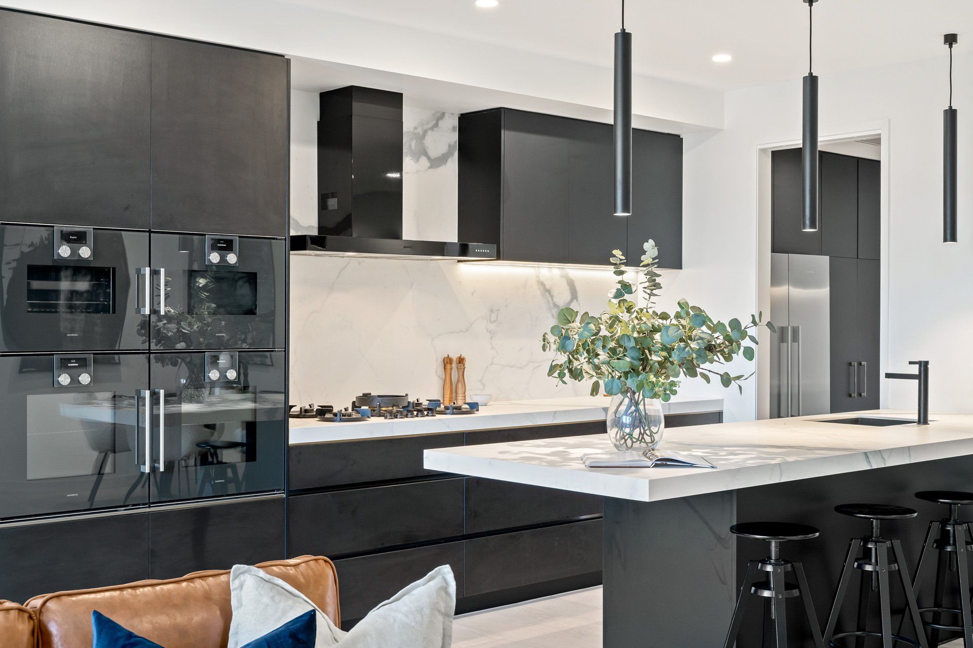 A kitchen with black cabinets and a marble counter top.