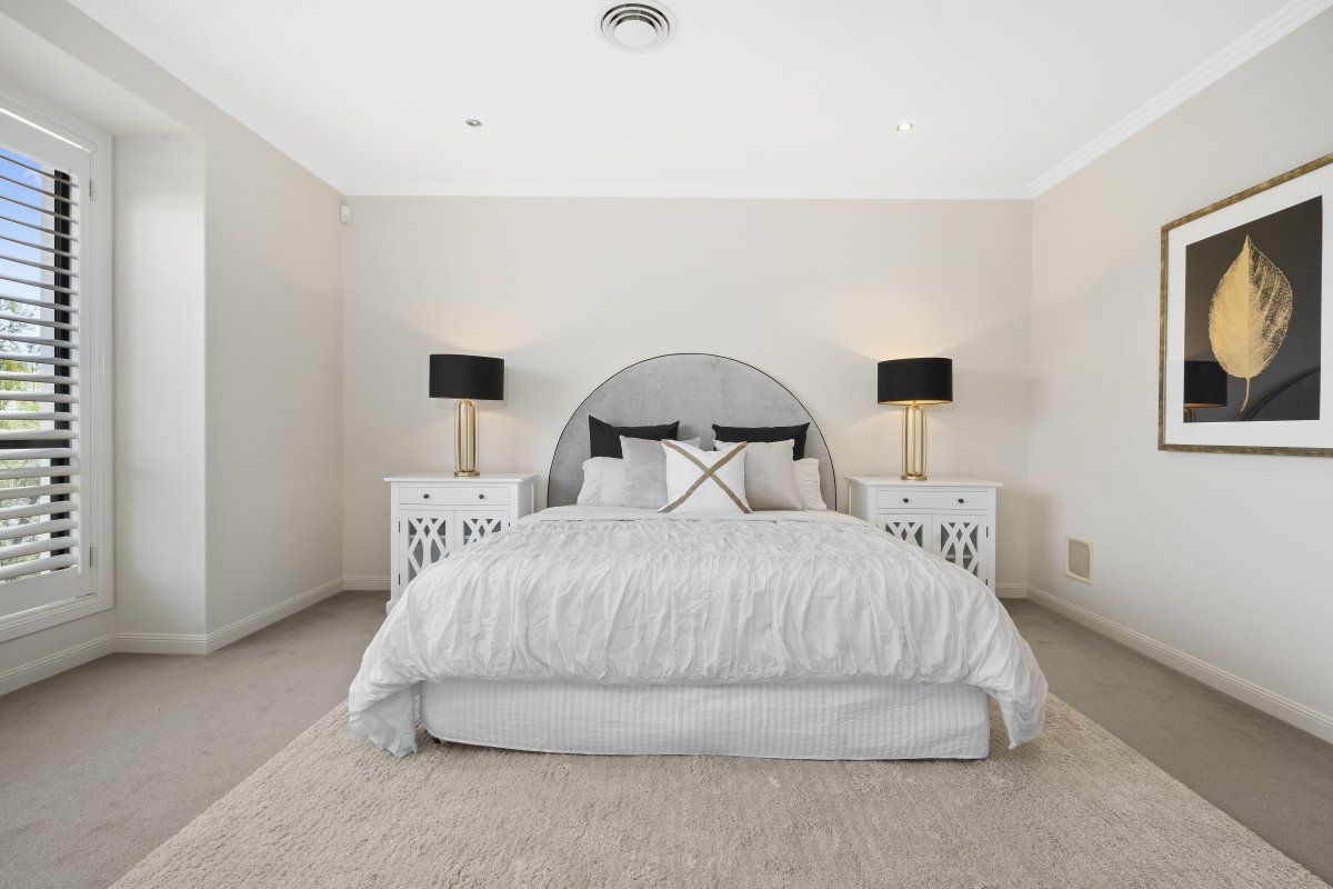 A bedroom with a bed , nightstands , lamps and a picture on the wall.