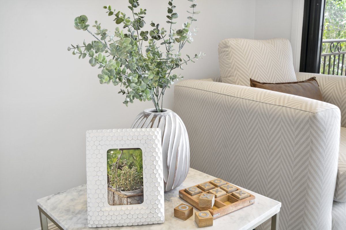A living room with a couch and a table with a vase of flowers and a picture frame on it.