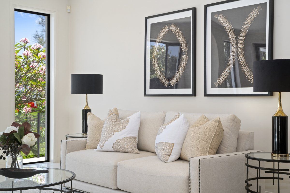 A living room with a couch , lamps , and a window.