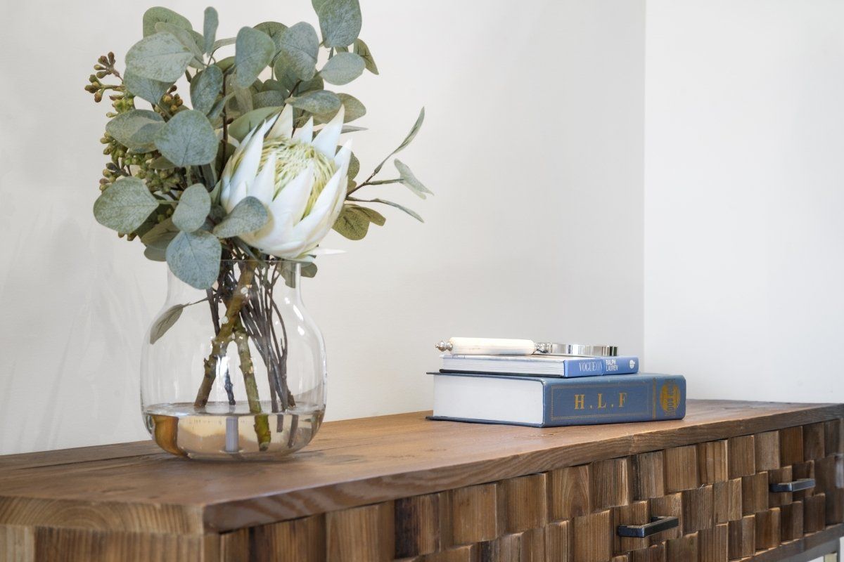 A vase of flowers is sitting on a wooden table next to a book.