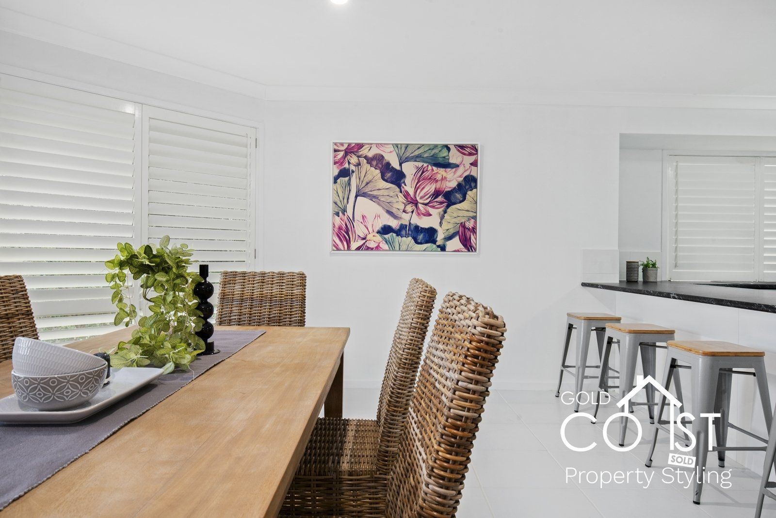 A dining room with a table and chairs and a painting on the wall.