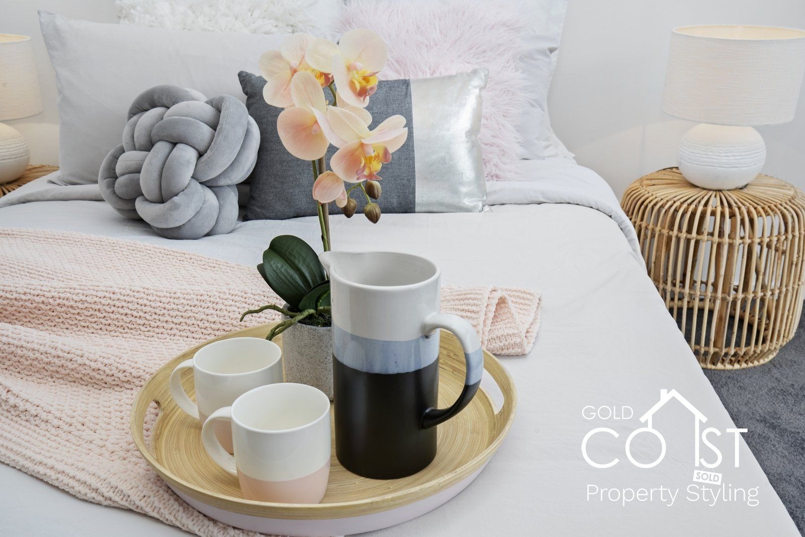 A bed with a tray of coffee cups and a pitcher on it.