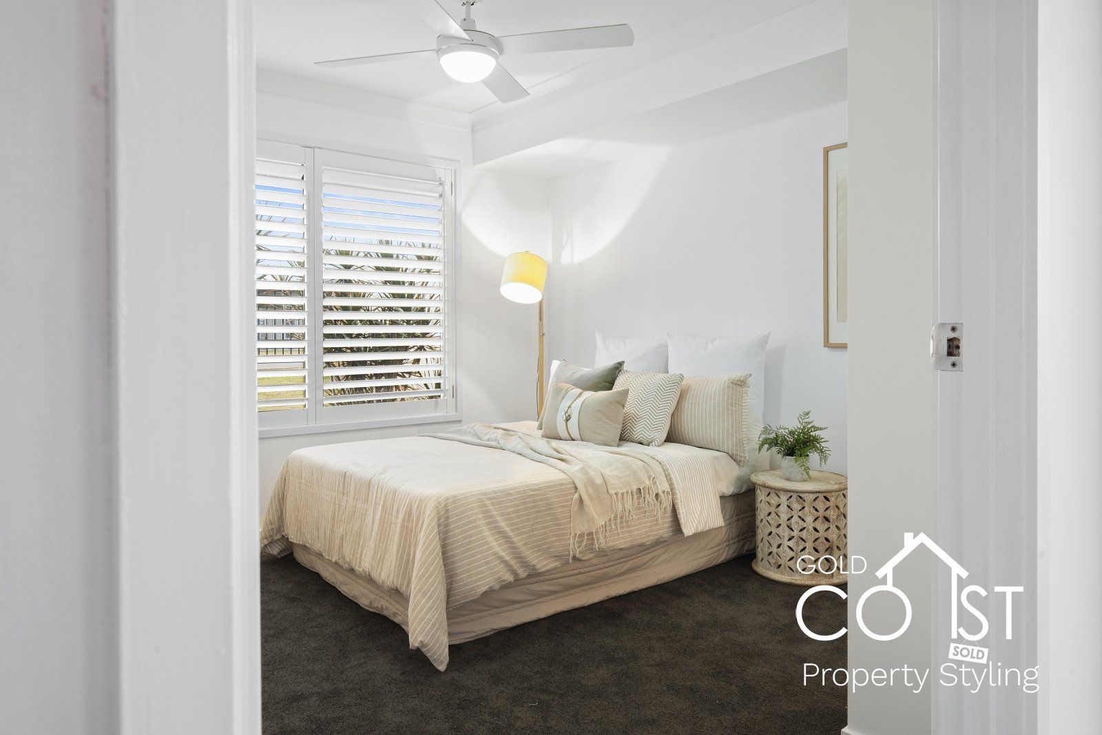 A bedroom with a bed , nightstand , lamp and ceiling fan.