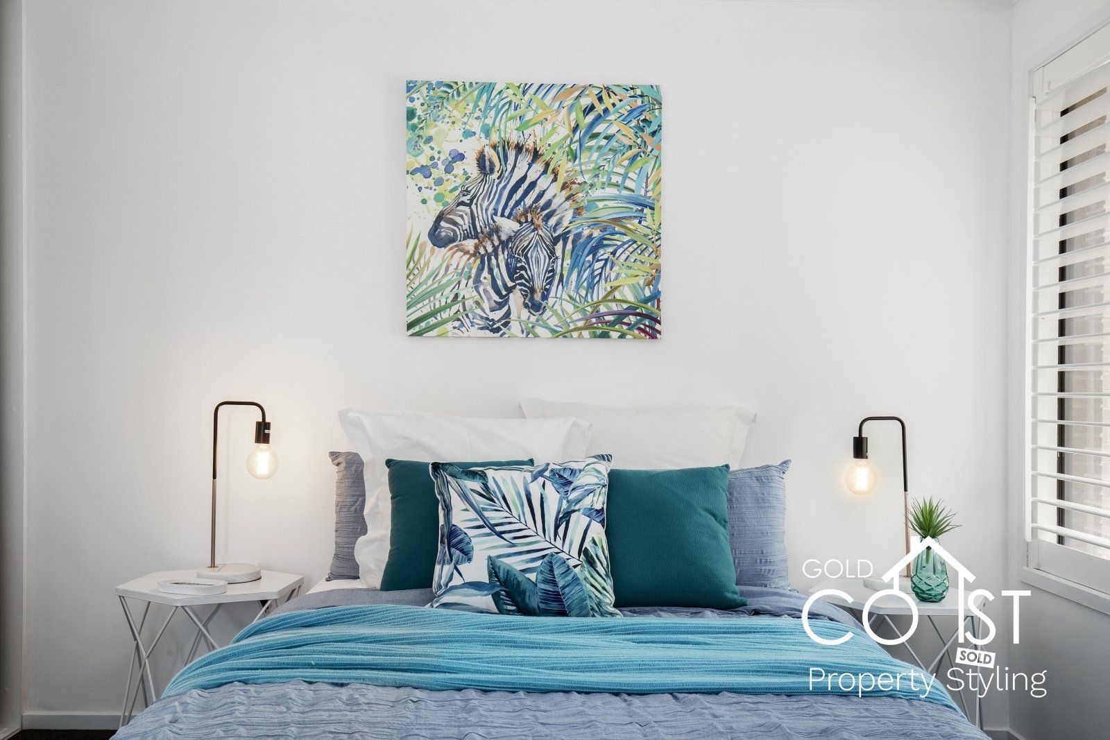 There is a painting of a zebra on the wall above the bed.