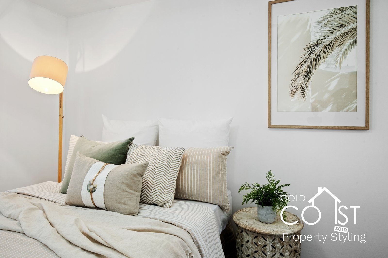 A bedroom with a bed , pillows , a lamp and a picture on the wall.
