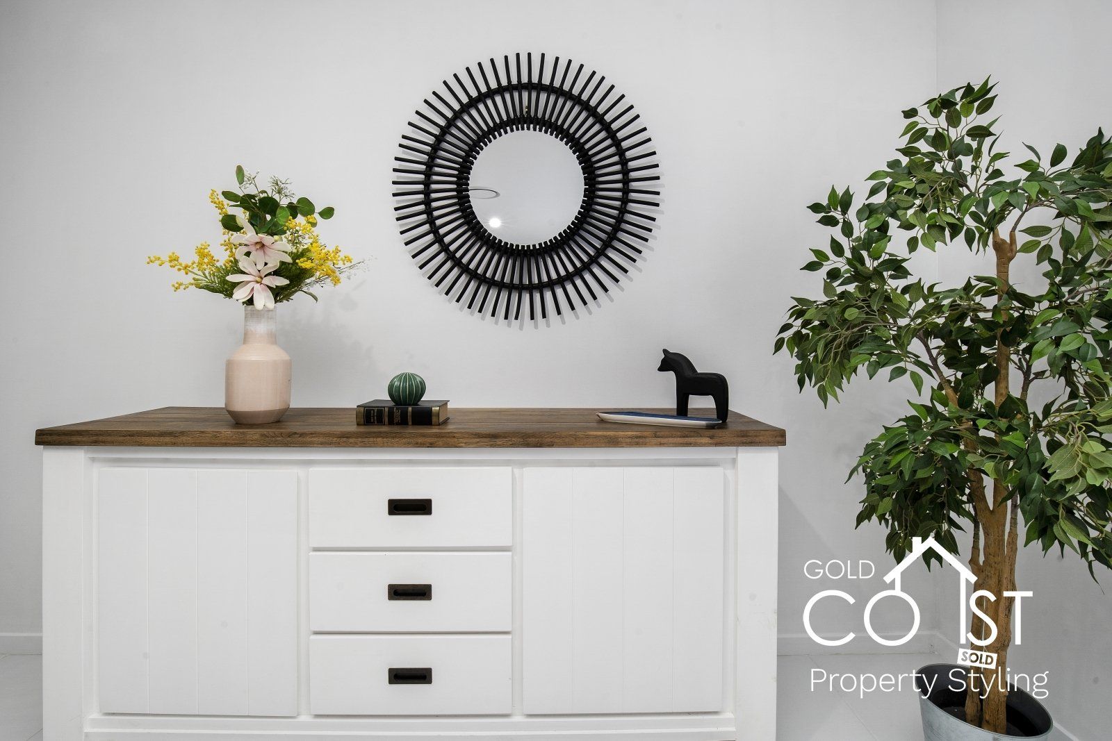 A white dresser with a wooden top and a mirror on the wall.