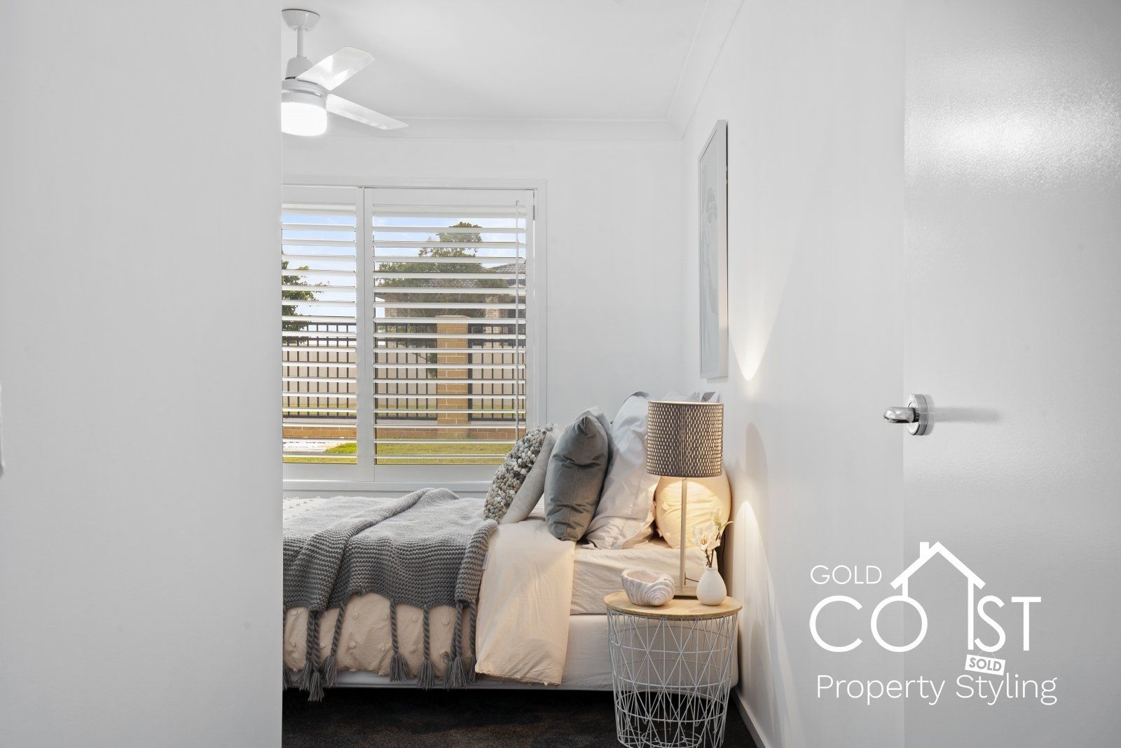A bedroom with a bed , nightstand , lamp and ceiling fan.