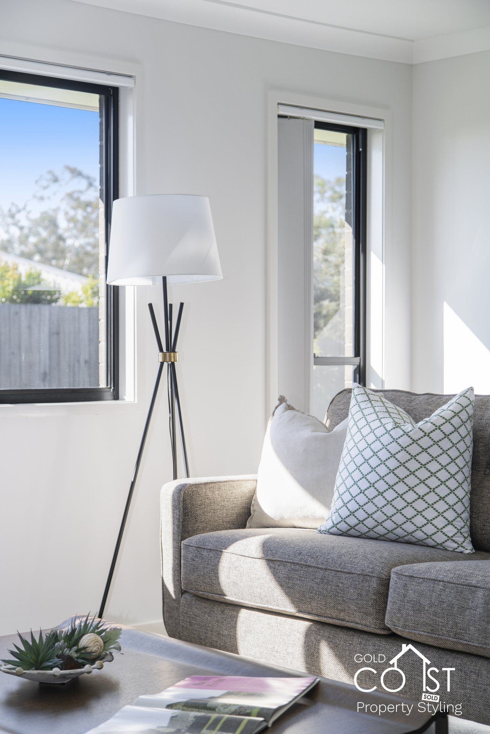 A living room with a couch , table , lamp and window.