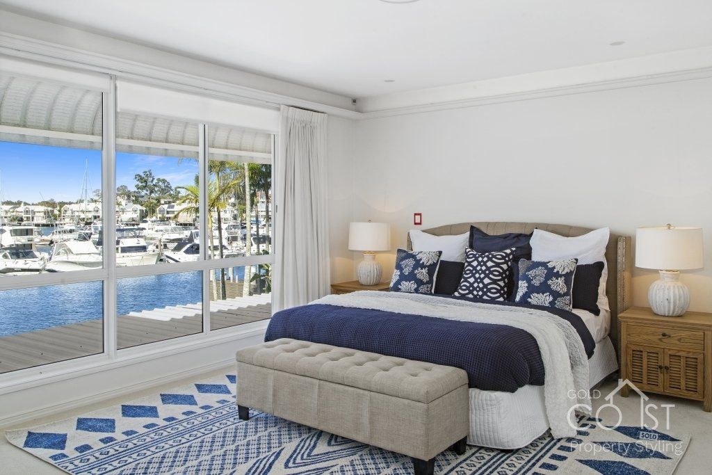 A bedroom with a large bed and a large window overlooking the water.