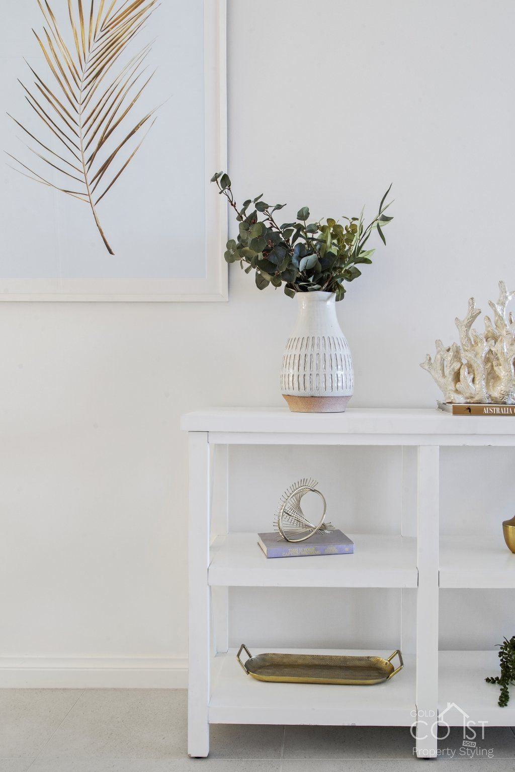 A white shelf with a vase of flowers on top of it.