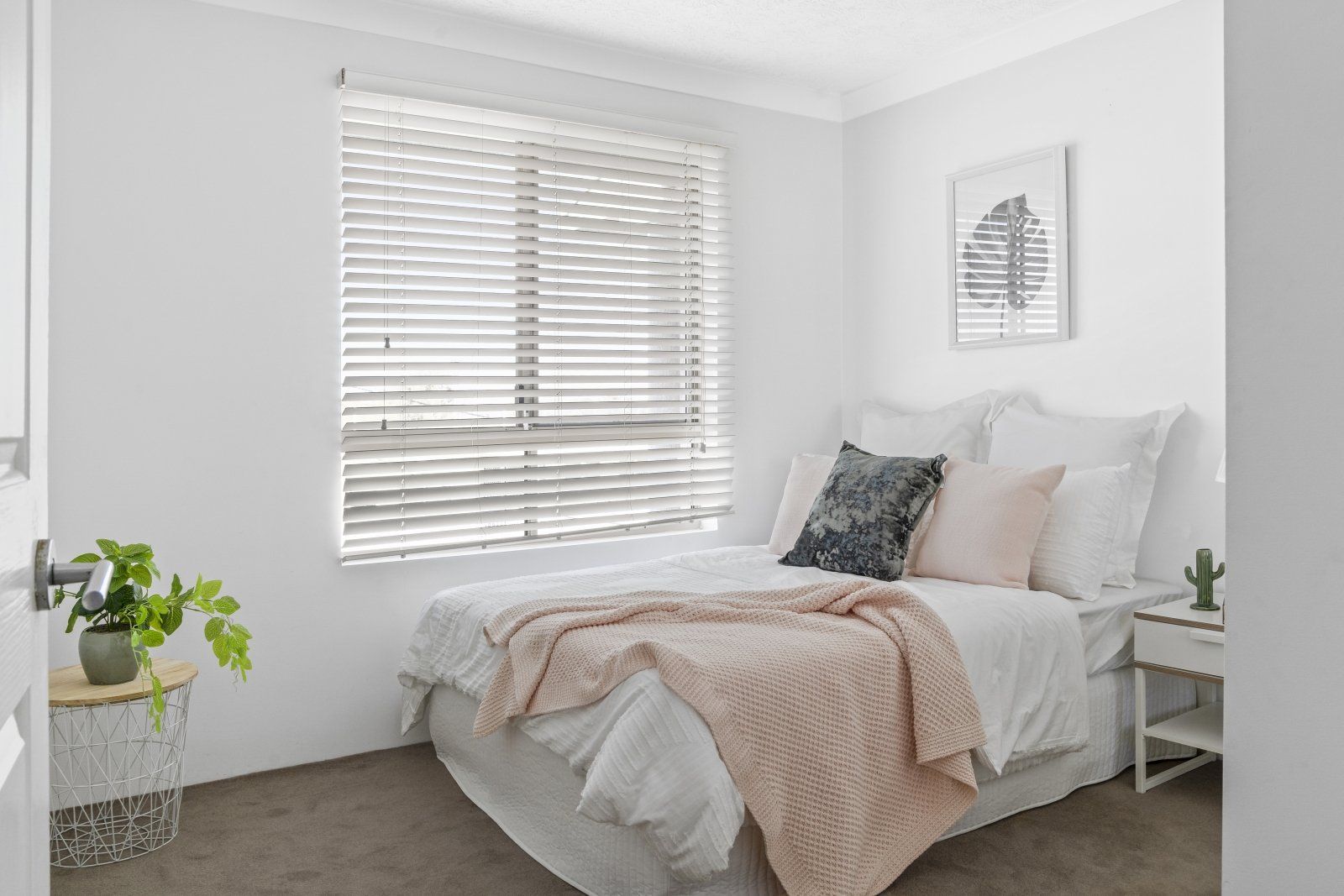 A bedroom with a bed and a window with blinds.