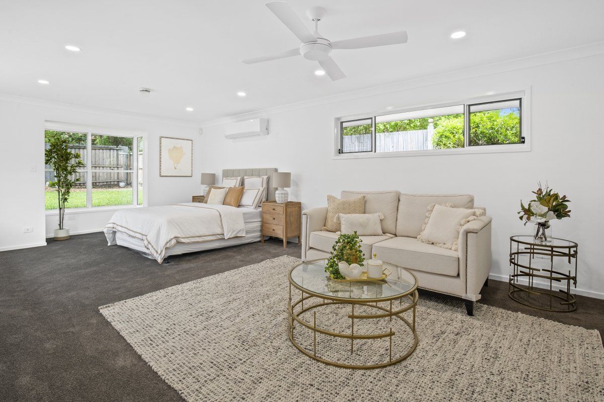 A living room with a bed , couch , coffee table and ceiling fan.