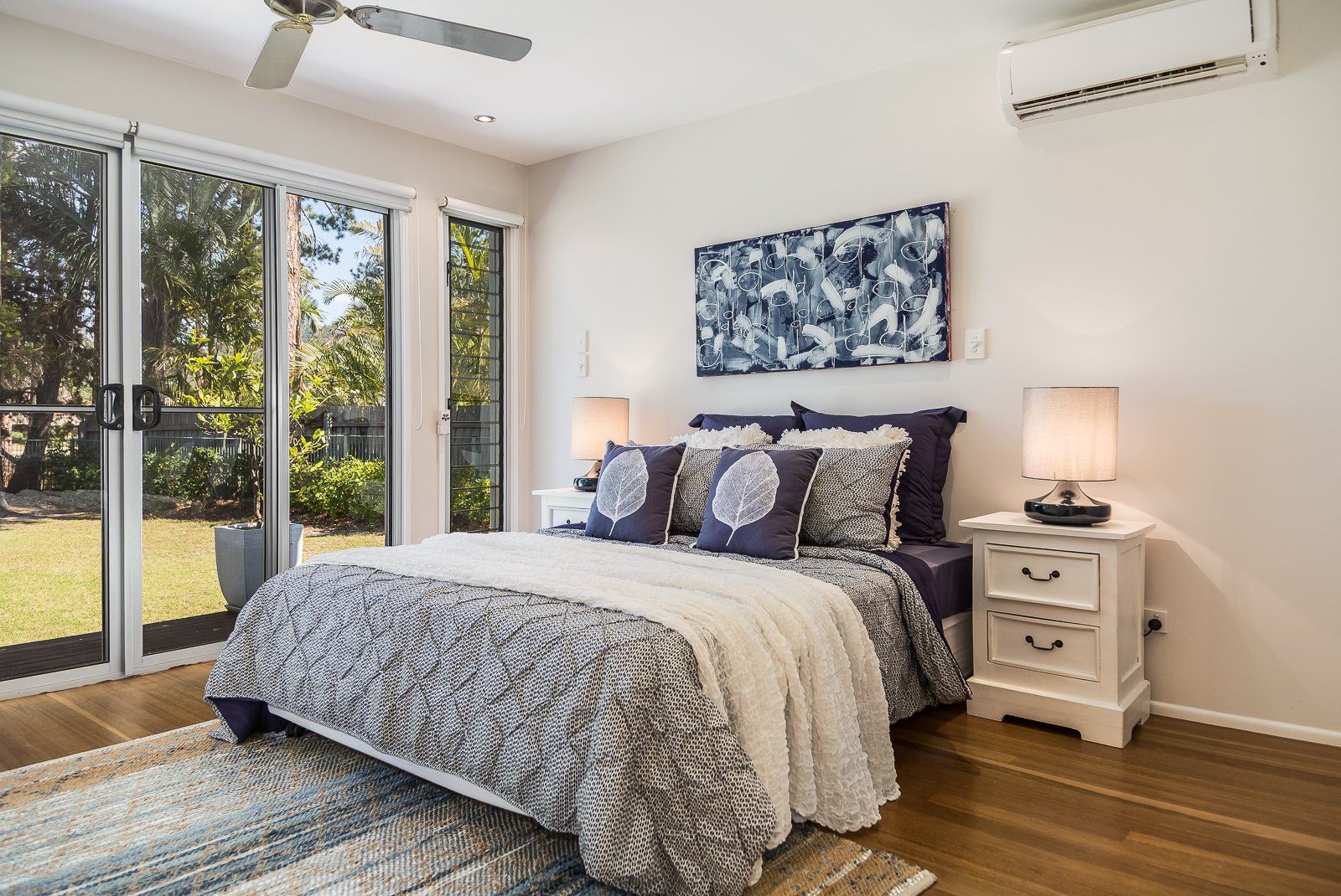 A bedroom with a king size bed , nightstands , and a ceiling fan.