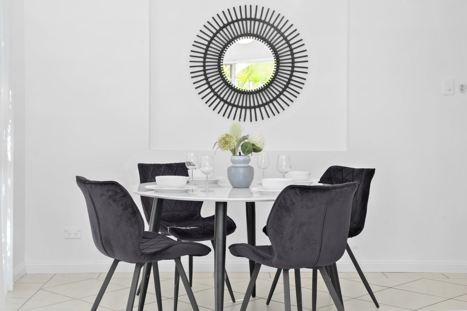 A dining room with a table and chairs and a mirror on the wall.