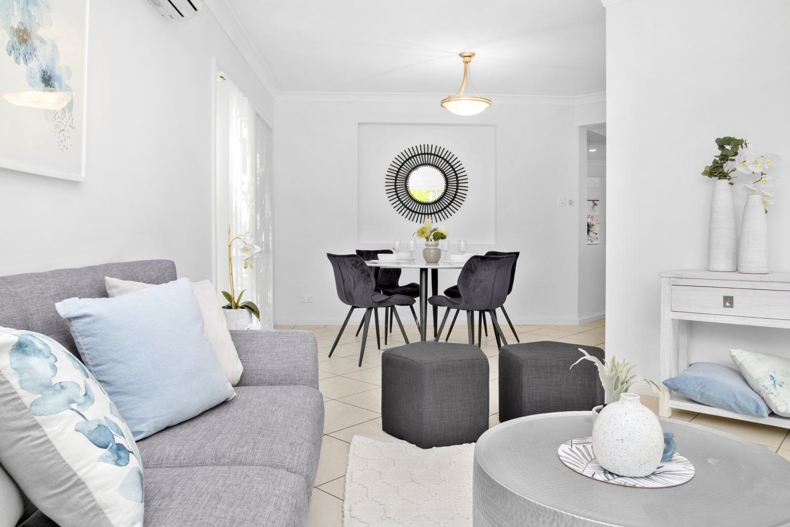 A living room with a couch , table and chairs and a dining room in the background.