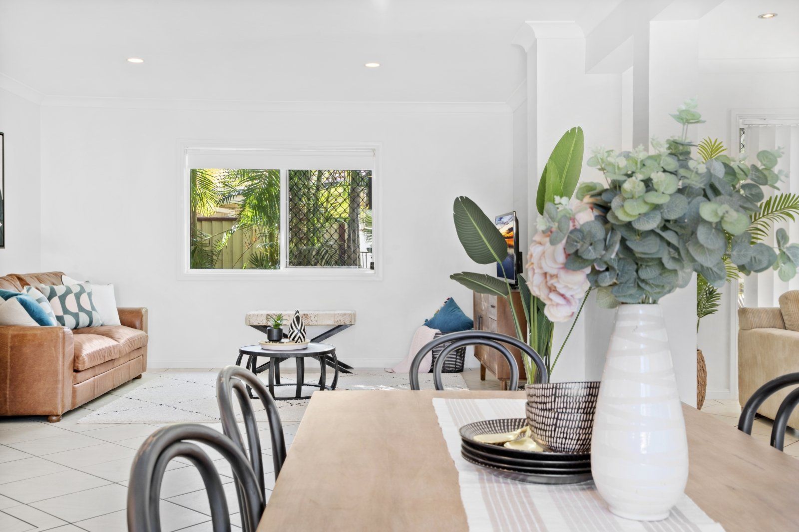 A dining room table with a vase of flowers on it in a living room.