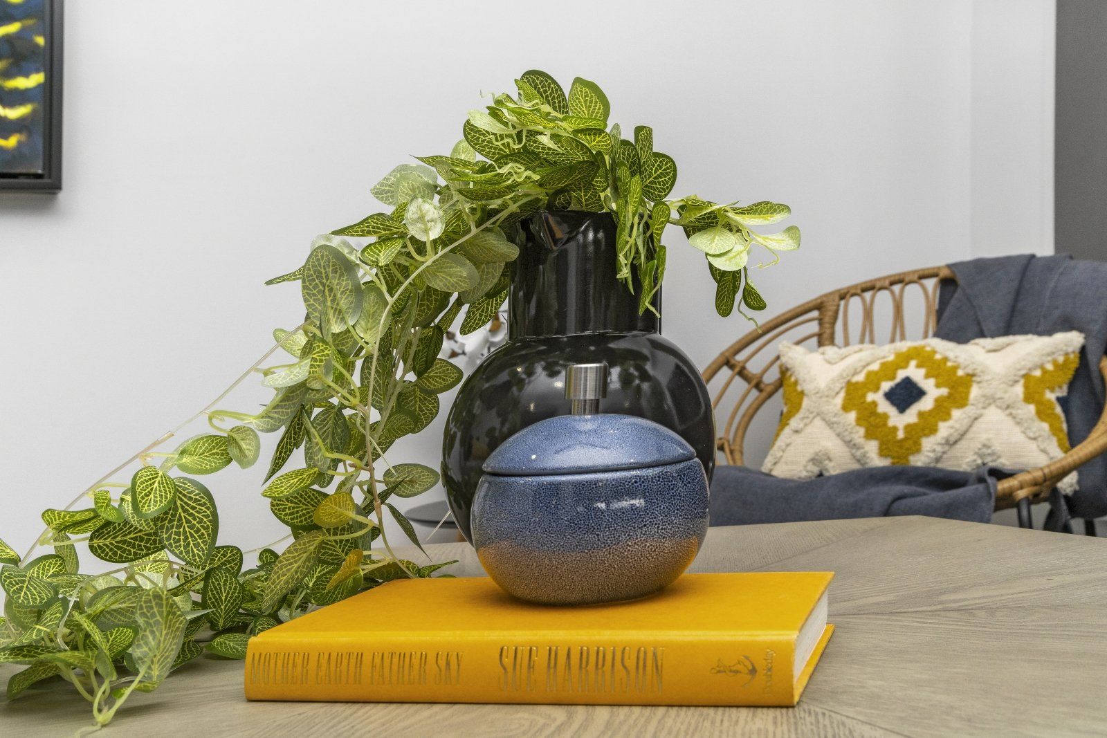 A book is sitting on a table next to a vase and a plant.