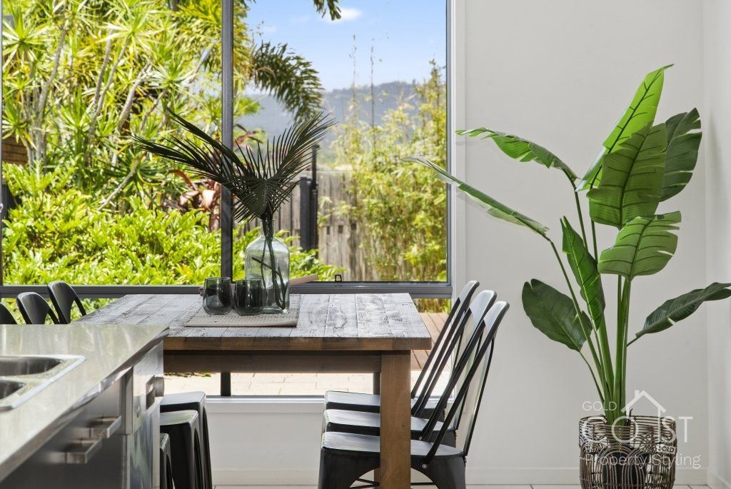 A dining room with a table and chairs and a potted plant.