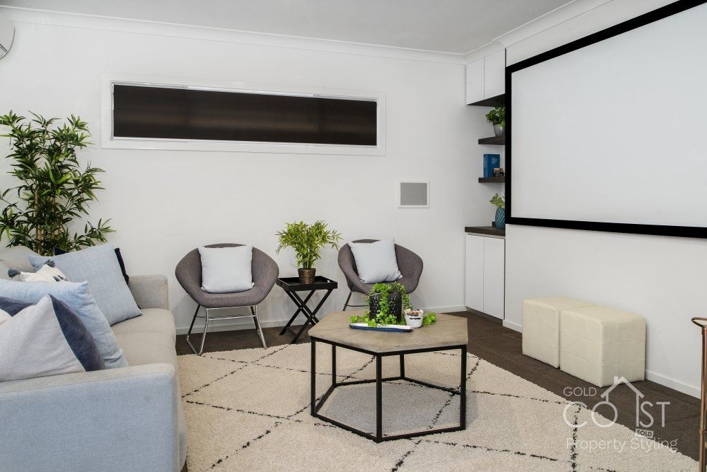 A living room with a couch and chairs and a projector screen