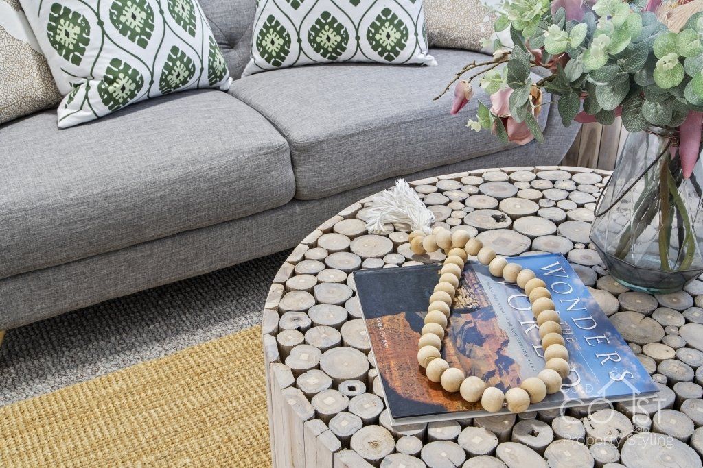 A living room with a couch and a coffee table with a vase of flowers on it.