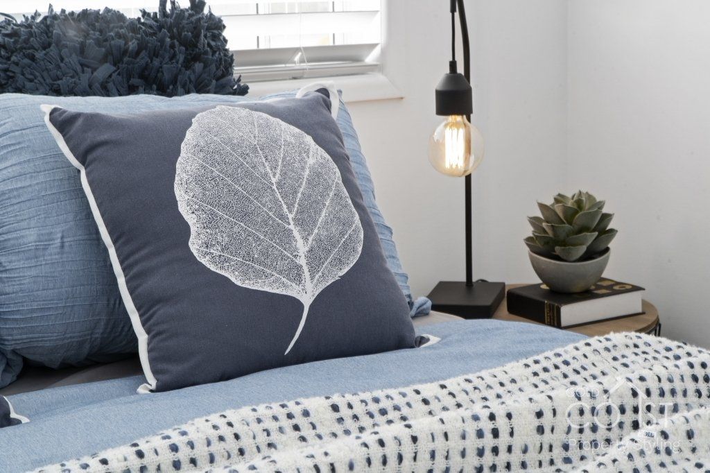 A bed with a pillow that has a leaf on it