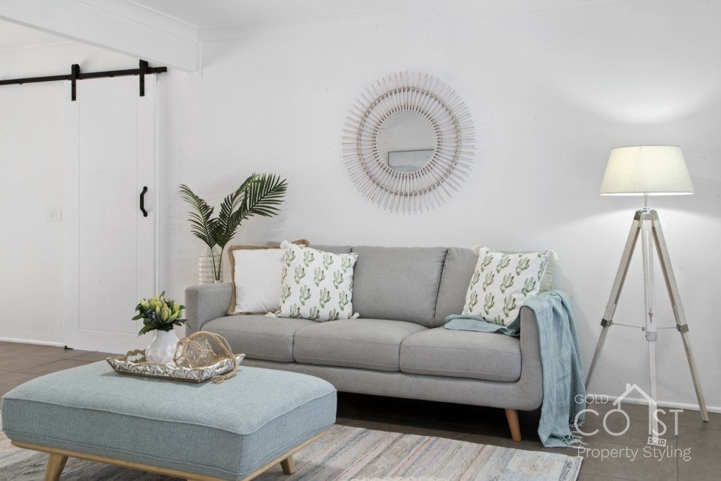 A living room with a gray couch and a blue ottoman
