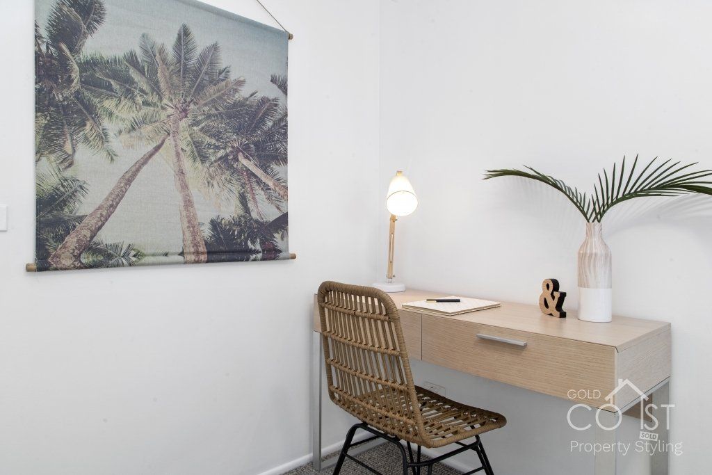 There is a picture of palm trees on the wall above the desk.