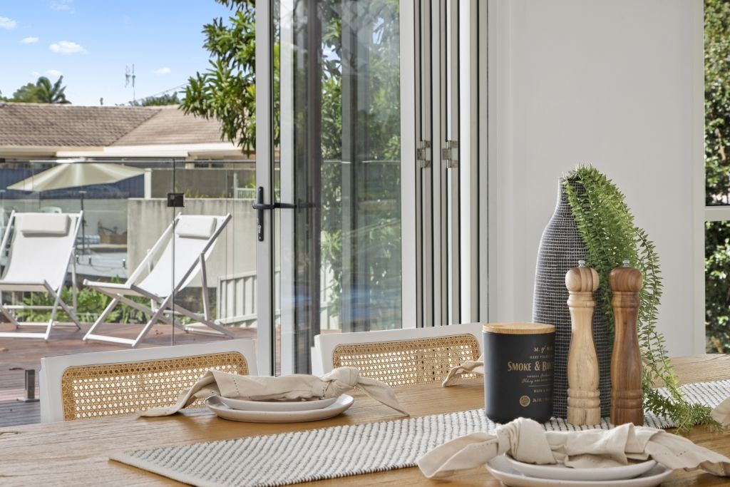 A dining room table with plates and napkins on it and a view of a pool.
