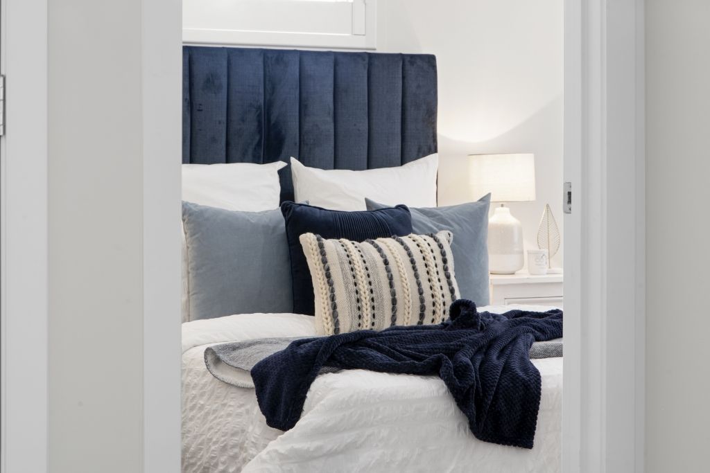 A bedroom with a bed , headboard , pillows and a window.