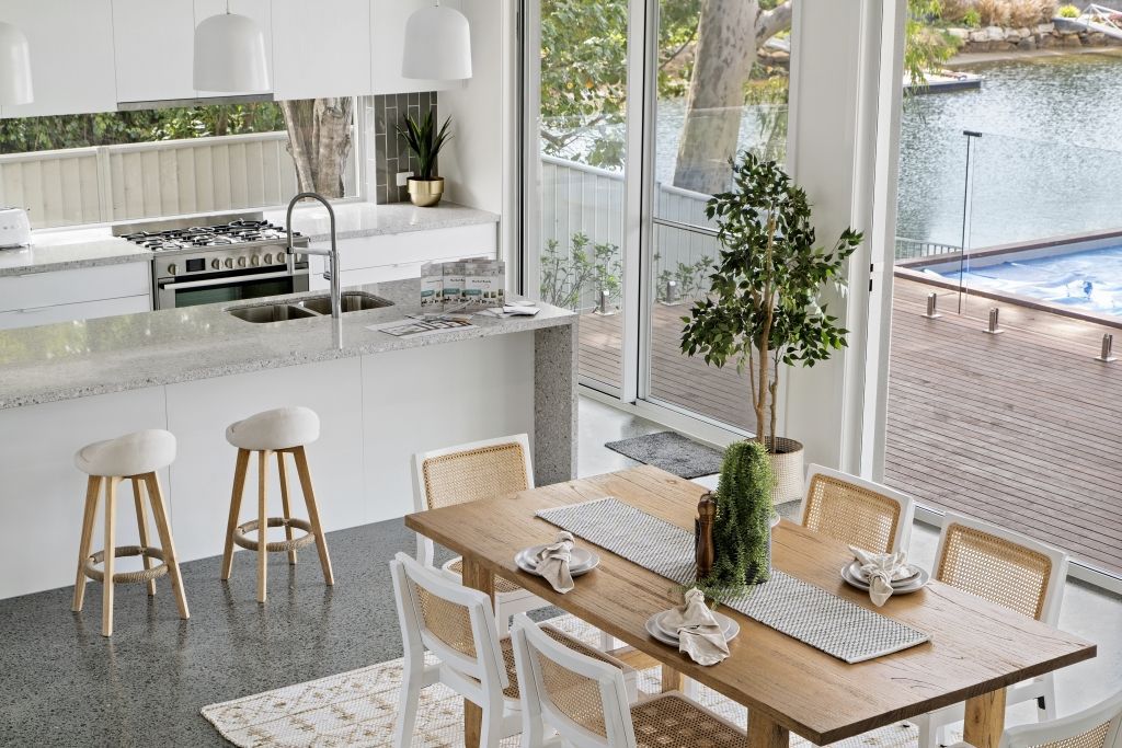 A dining room table and chairs in a kitchen with a view of a pool.