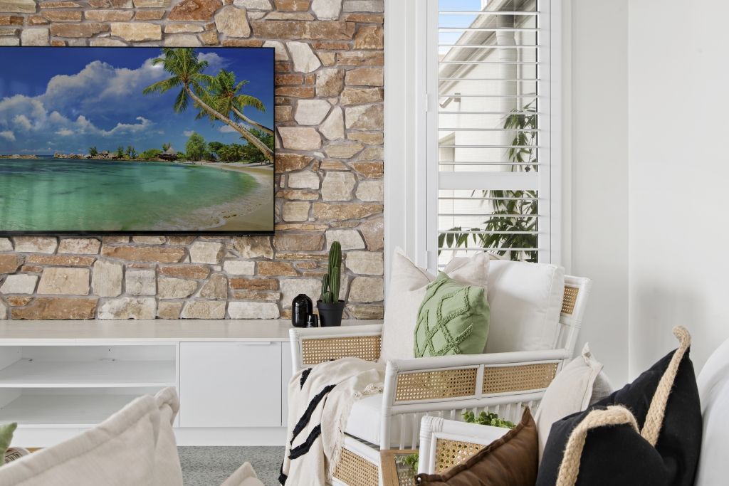 A living room with a couch , chair , and television on the wall.