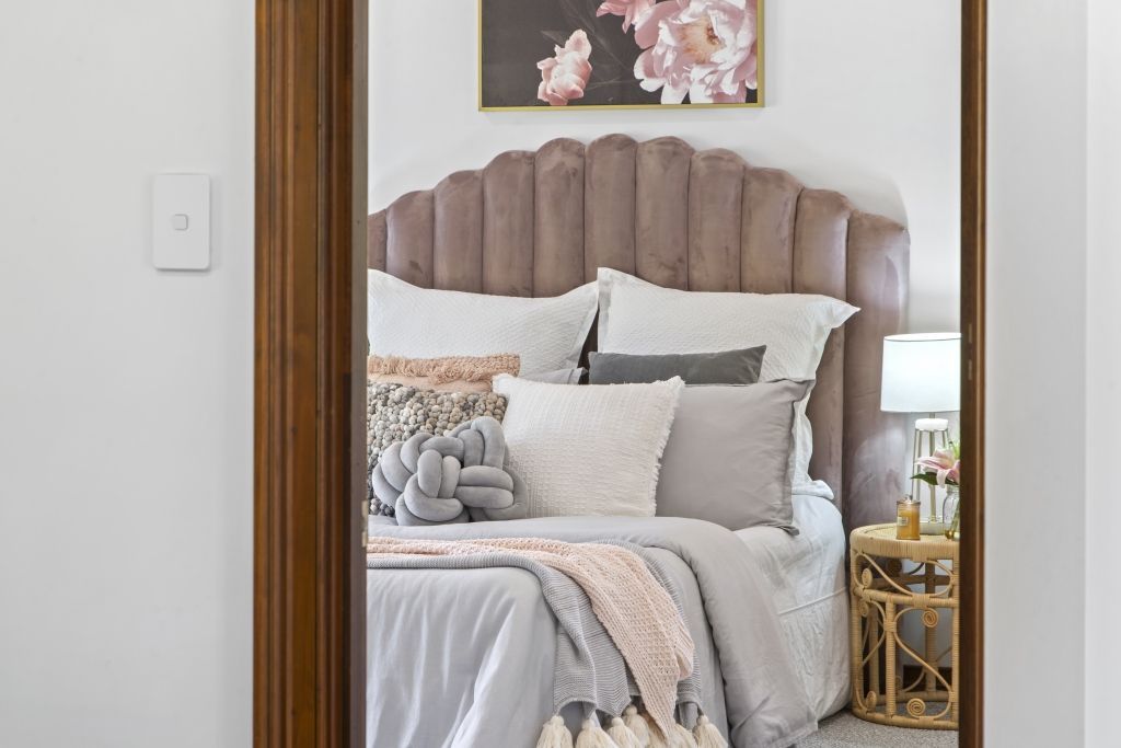 A bedroom with a full length mirror and a bed.