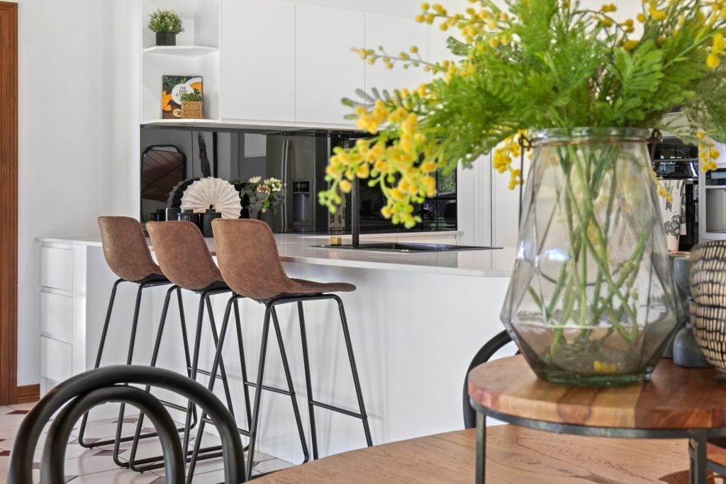 There is a vase of flowers on the table in the kitchen.