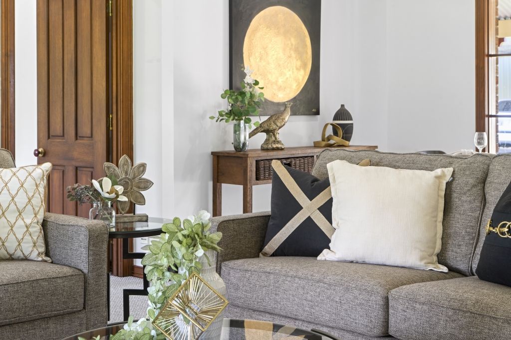 A living room with a couch , two chairs , a coffee table and a painting on the wall.