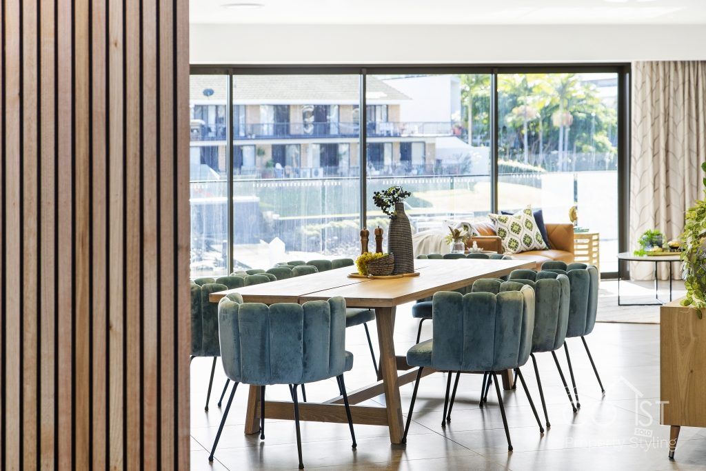 A dining room with a long table and chairs and a large window.