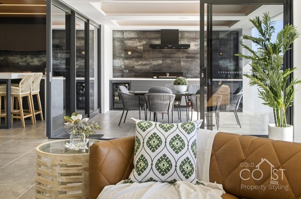 A living room with a brown couch and a green pillow on it.