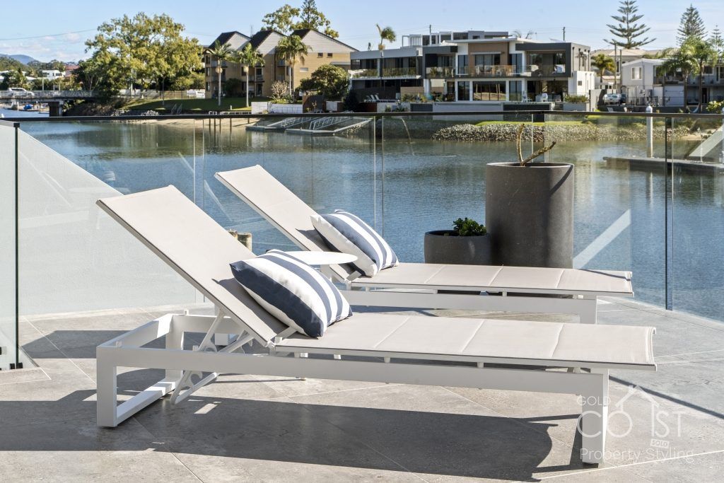 A couple of lounge chairs sitting next to a body of water