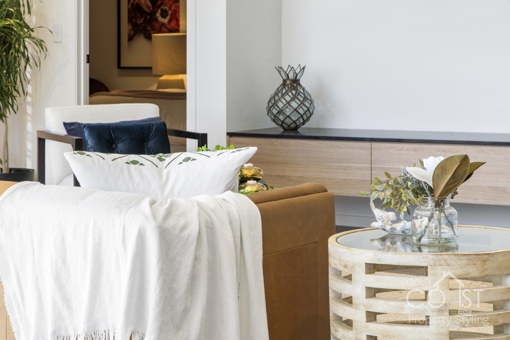 A living room with a couch , chair , table and vases.