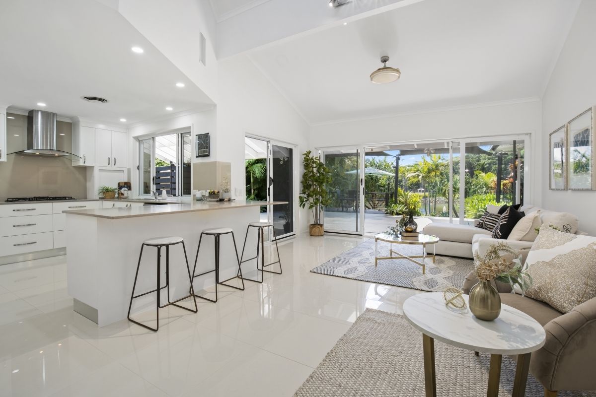 A living room with a couch , table , stools and a kitchen.