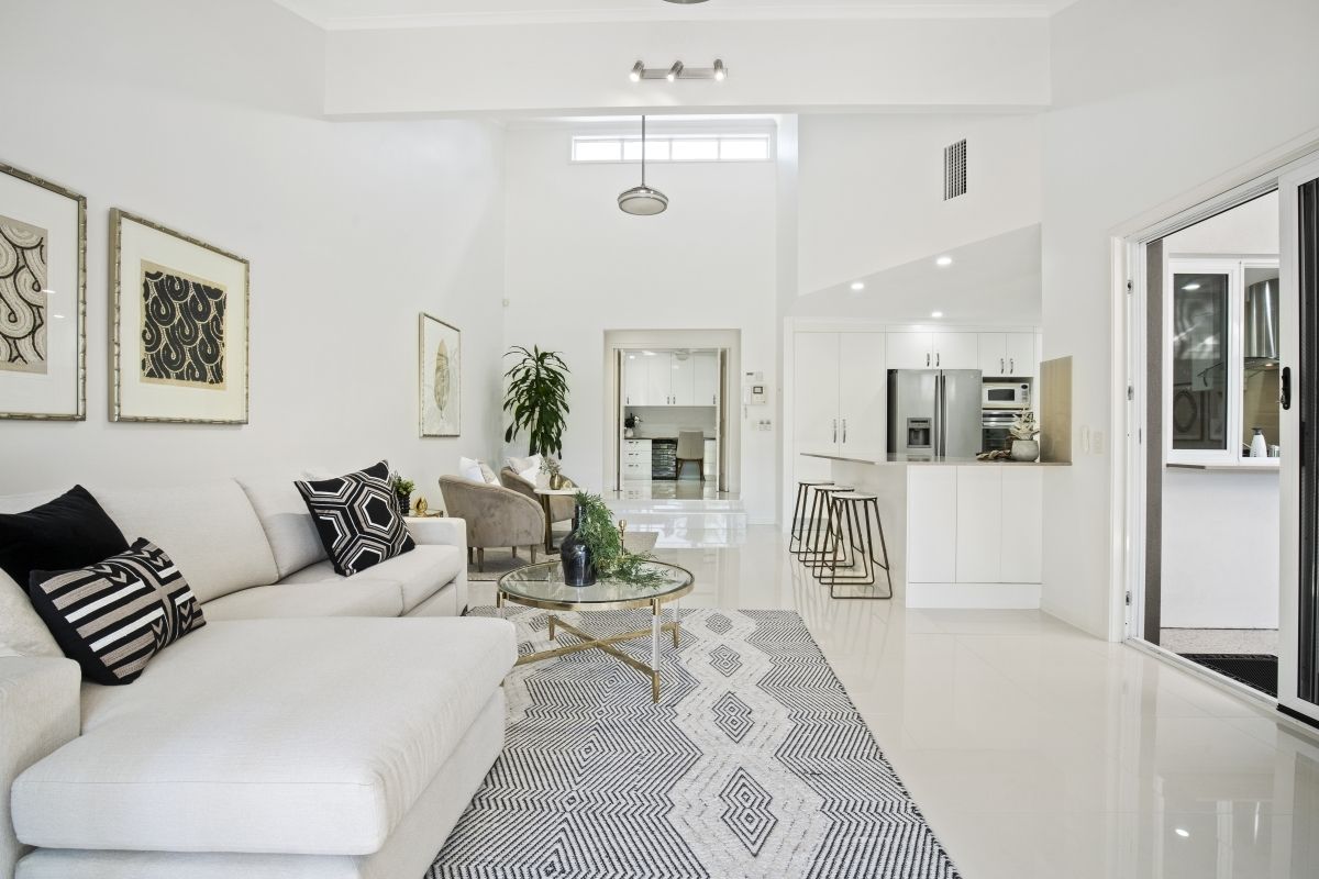 A living room with a white couch and a black and white rug.