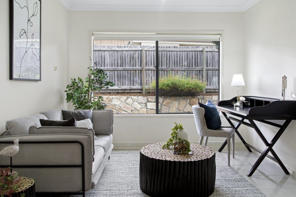 A living room with a couch , chair , coffee table and desk.